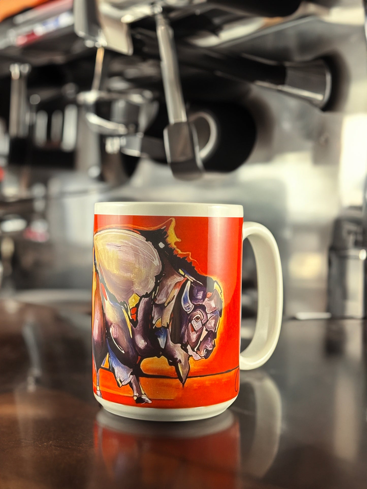 A striking ceramic mug featuring Andrew French’s “Buffalo” artwork. The design showcases a bold and expressive painting of a buffalo in motion against a fiery orange background, blending Western energy with modern artistry.