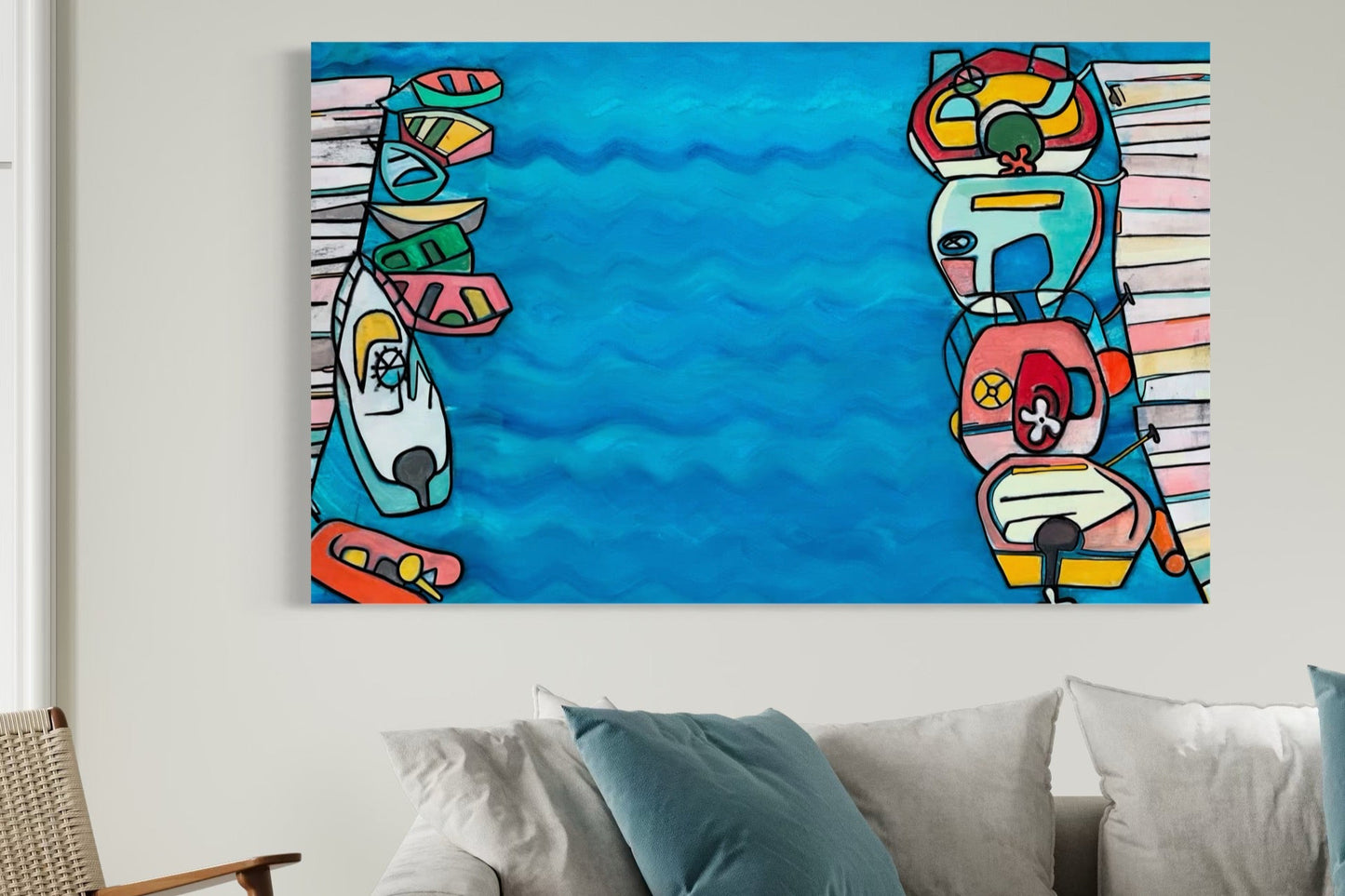 “Docked and Drenched in Color” by Andrew French displayed above a cozy modern sofa, showcasing its vibrant pastel boats and serene blue water tones for a bright, calming statement piece.