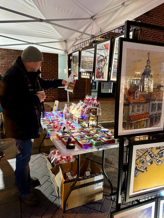 Midnight Madness Vendor Market Street Merchants set up and a customer is picking up a holiday coffee mug set to purchase