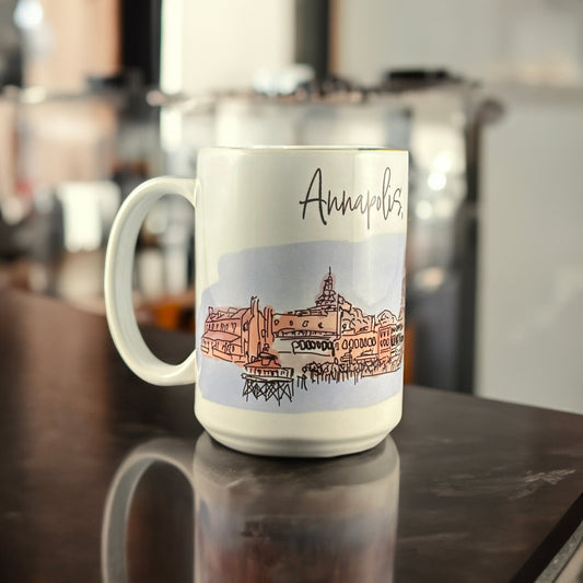 A white ceramic mug featuring an original hand-drawn illustration of downtown Annapolis, Maryland, by Andrew French. The design captures the charm of the Chesapeake and the city’s nautical heritage, blending everyday function with coastal artistry.