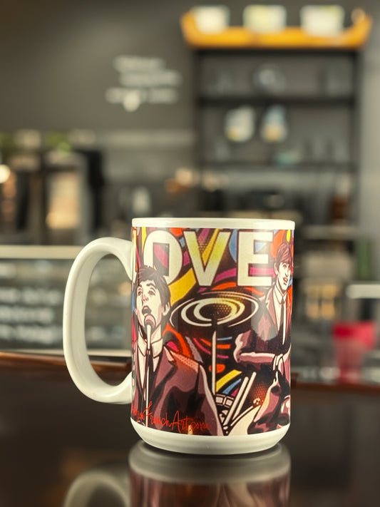 A colorful ceramic mug featuring Andrew French’s Beatles-inspired artwork. The design showcases vibrant pop art illustrations of the iconic band members performing, surrounded by bold lettering that reads “LOVE,” blending nostalgia and artistry in a collectible mug for music fans.