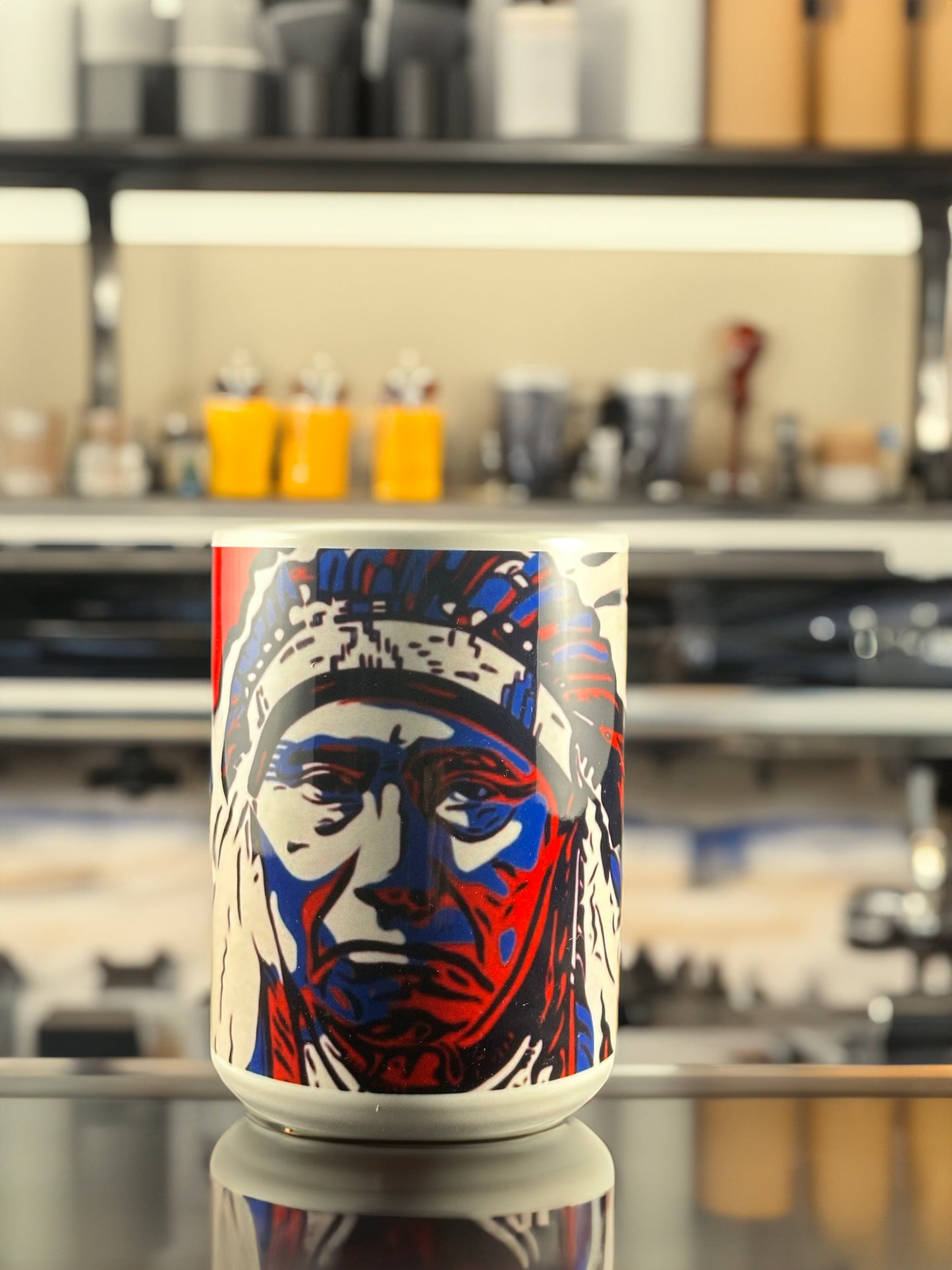 A bold ceramic mug featuring Andrew French’s “Chief” artwork. The design highlights a striking red, white, and blue portrait of a Native American chief, rendered in a modern, graphic-art style that blends cultural strength with contemporary design.