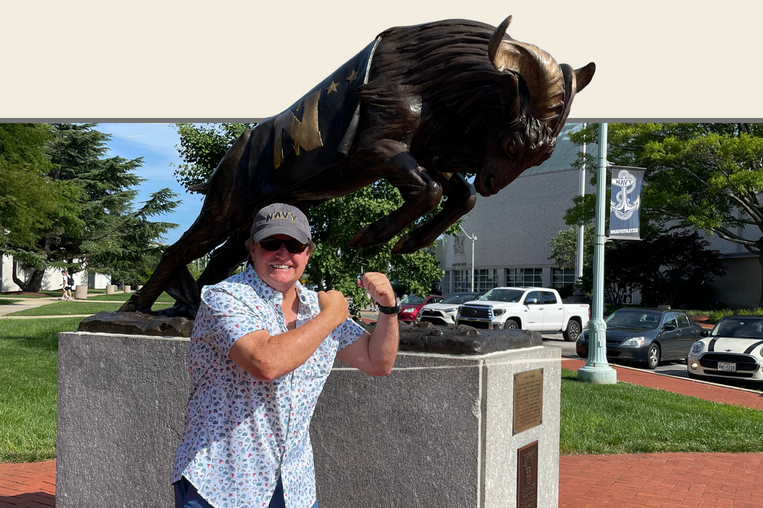 Dan West posing in front of the U.S. Naval Academy’s bronze buffalo statue in Annapolis, Maryland, wearing a Navy cap and smiling proudly. The image highlights his connection to military heritage and local Annapolis pride.