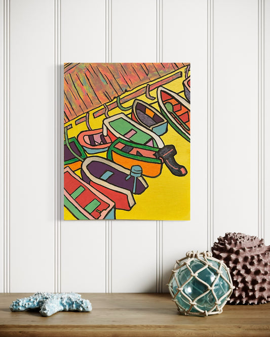 “Harbor” by Andrew French displayed above a coastal-inspired table with seashell and nautical décor, highlighting its bold yellow tones and boat details.