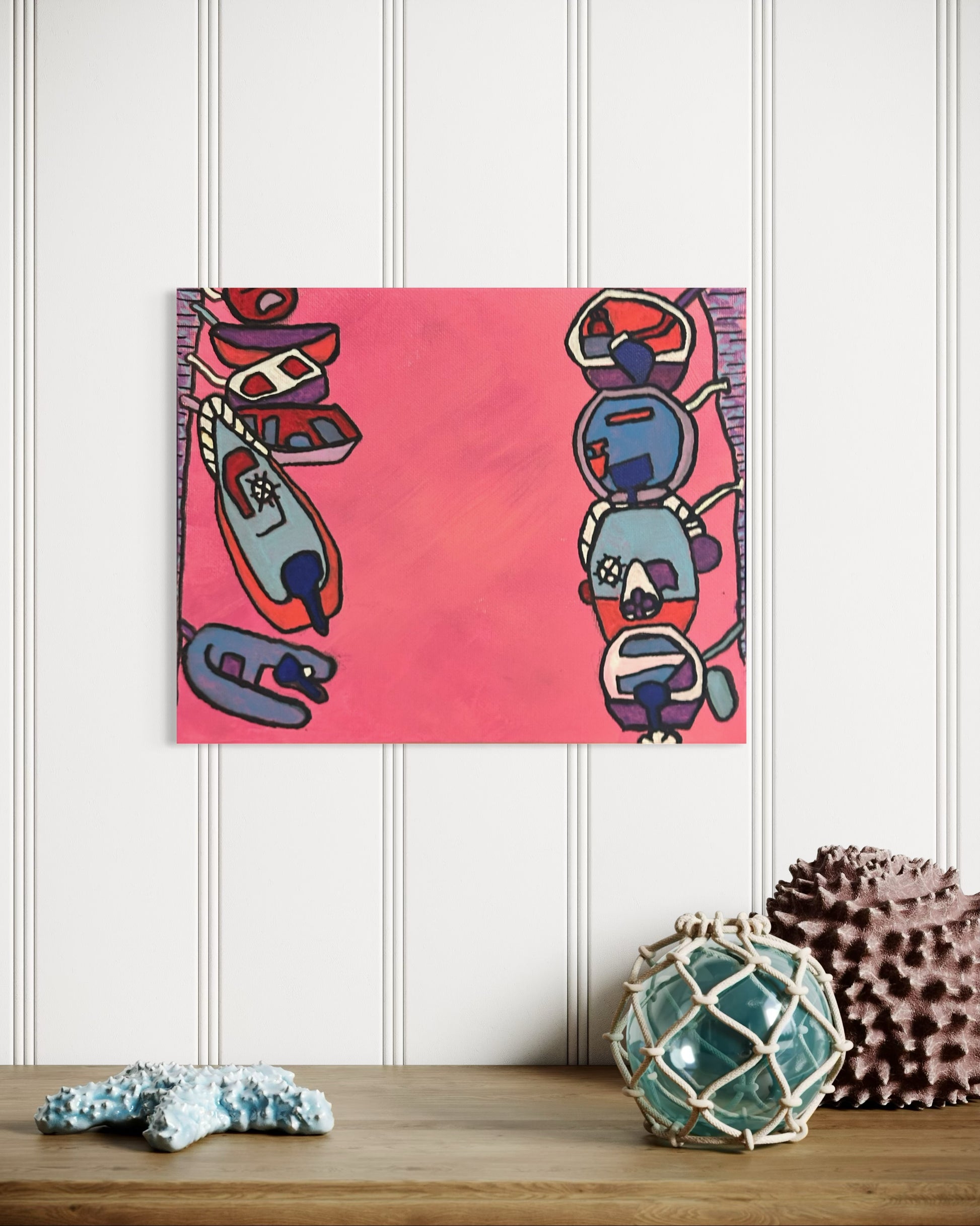 “Playful” by Andrew French displayed above a wooden console table with ocean-inspired décor, showing off its vivid pink tones and nautical abstract charm.