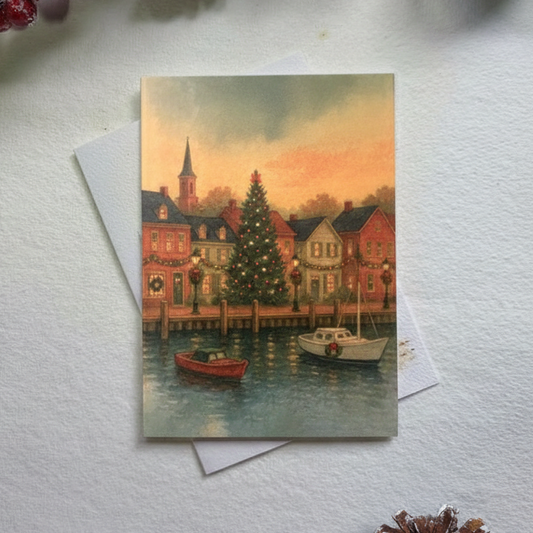 Vintage-style Christmas card with a village scene on a white surface with decorative elements.