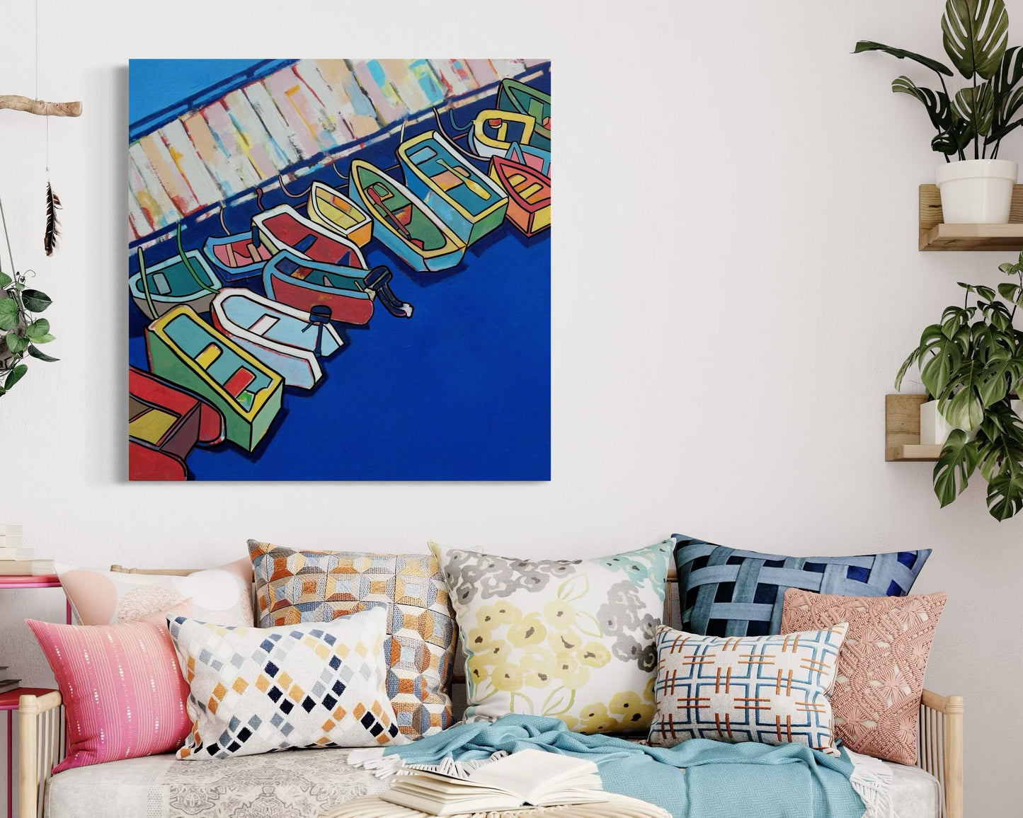 “Serenity Harbor” by Andrew French displayed in a cozy, coastal-inspired living space with patterned pillows, rattan furniture, and plants, adding vibrant color and maritime charm to the décor.